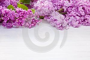 Spring lilac flowers as frame on white wooden table background, copy space