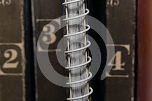 A spring-loaded notebook among old brown books