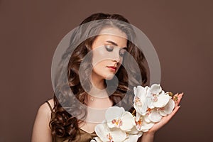 Spring model woman portrait. Beautiful female with long perfect curly hair and white flowers