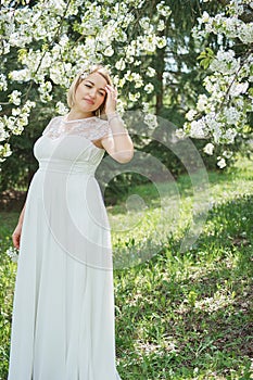 Spring mood, beautiful pregnant woman smell flowering cherry tree, enjoying nature, white floral garden