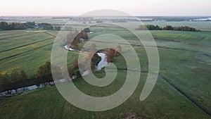 Spring morning landscape. Calm river in blooming meadows. Aerial rural view