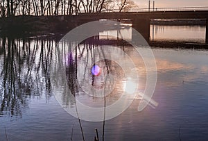 Spring morning on the river.The sun, clouds and trees are reflected in the water.