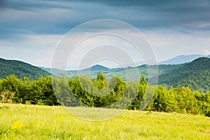 Spring in mountains.Contrast colors.Sunny glade and blue mountains.