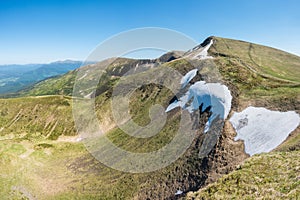 Spring mountains with patches of snow under a blue sky