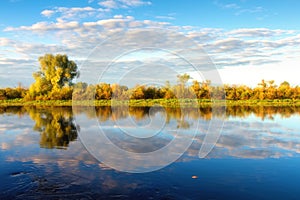 Spring nature landscape on the riverside in morning. Warm sunlight on trees along the river. Fresh scenic spring nature. Trees