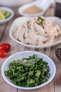 Spring onions and sliced â€‹â€‹guava in a white cup on a wooden table