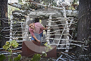 In the spring in a pine forest, the boy built a hut of sticks