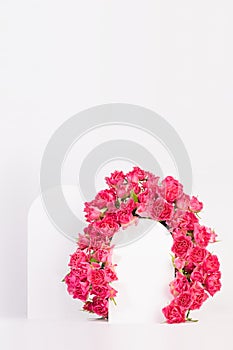 Spring pink flowers - roses as framing of arch with two podiums on abstract white stage mockup for showing of cosmetic products.