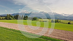 Spring plowed field in rural agriculture nature, farming in green alpine landscape