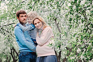 Spring portrait of happy family enjoying holidays in blooming garden