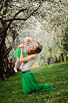 Spring portrait of mother and baby daughter playing outdoor in matching outfit - long skirts and shirts