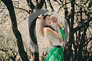 Spring portrait of mother and baby daughter playing outdoor in matching outfit - long skirts and shirts