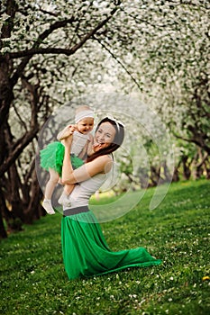 Spring portrait of mother and baby daughter playing outdoor in matching outfit - long skirts and shirts