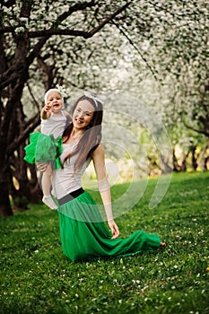 Spring portrait of mother and baby daughter playing outdoor in matching outfit - long skirts and shirts