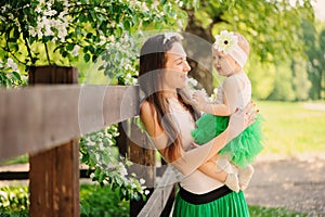 Spring portrait of mother and baby daughter playing outdoor in matching outfit - long skirts and shirts