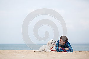 Spring portrait of a young man with a dog on the beach