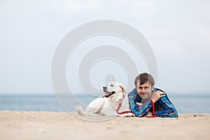 Spring portrait of a young man with a dog on the beach