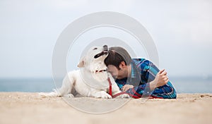Spring portrait of a young man with a dog on the beach