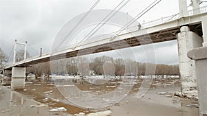 Spring river with dirty brown water and ice. floating of ice and bridge