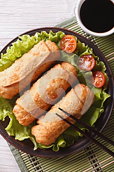 Spring rolls fried on lettuce close-up, vertical top view