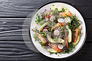 Spring salad of salmon, avocado, radish and mix microgreen close-up on a plate. horizontal top view photo