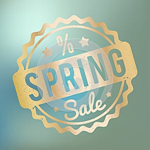 Spring Sale rubber stamp gold on a blue bokeh background.