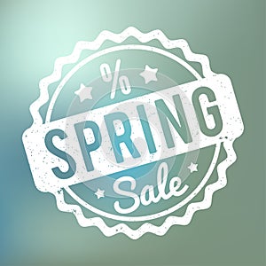 Spring Sale rubber stamp white on a blue bokeh background.