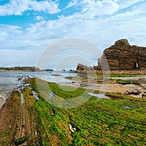 Spring sea rocky coast view with hole in rock and algae on stone Playa Del Portio, Biskaya, Cantabria, Spain photo