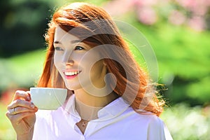 Spring smile. Happy beautiful smiling young woman cup coffee in blossom park.