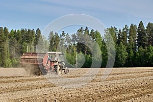 Spring sowing in potato field, potato planter plants potatoes using wheeled tractor.