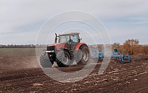 Spring sowing season. Farmer with a tractor sows corn seeds on his field. Planting corn with trailed planter