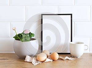 Spring still life. Blank picture frame mockup on wooden table background. Easter composition with Leucanthemum vulgare