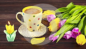 Spring still life with a white polka dot cup of coffee, a bouquet of yellow and pink tulip flowers and a candle erated image