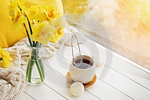 Spring still life with yellow flowers, tea and candle,