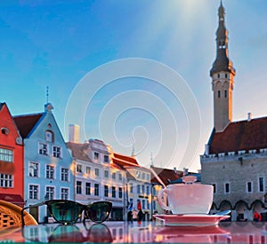 Spring street cafe in Tallinn old town medieval  tower on square , cup of coffee and sunglasses on table top view,sunset  in histo