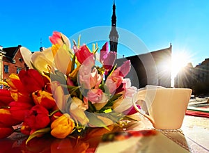 Spring street cafe in Tallinn town square ,cup of coffee on table top and flowers tulip sunlight reflection holiday travel to Esto