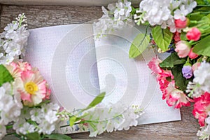 Spring and summer background.Flowers on a wooden texture with a Notepad for notes. Space for text