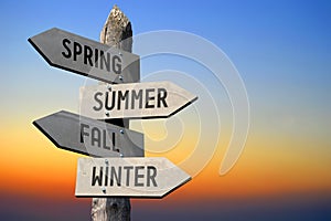 Spring, summer, fall, winter - wooden signpost, sunset sky