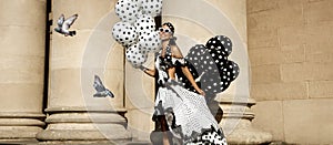 Spring, summer fashion. Glamour, stylish elegant woman in polka dot dress is holding balloons with dots. Female model in dress