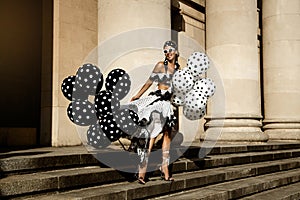 Spring, summer fashion. Glamour, stylish elegant woman in polka dot dress is holding balloons with dots. Female model in dress