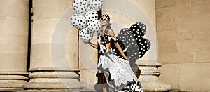 Spring, summer fashion. Glamour, stylish elegant woman in polka dot dress is holding balloons with dots. Female model in dress