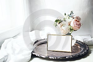 Spring, summer still life. Blank golden photo frame mockup on old silver tray near window. Vintage feminine styled photo