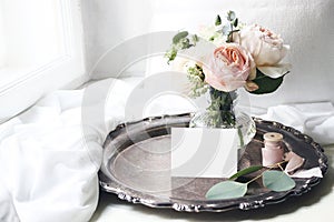 Spring, summer still life scene.Blank place card mockup on old silver tray at windowsill. Vintage wedding feminine