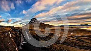 Spring sunrise over the famous Kirkjufellsfoss Waterfall with Kirkjufell mountain in the background in Iceland