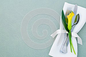 Spring Table Place Setting that is elegant and modern with copy space. It`s a horizontal flat layout with a yellow calla lily, si