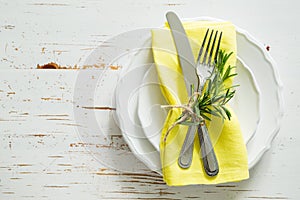 Spring table setting with rosemary and yellow napkin