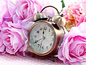 Spring time with alarm clock and artificial flowers bouquet background