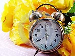 Spring time with alarm clock and artificial flowers bouquet background