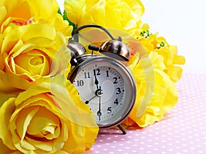 Spring time with alarm clock and artificial flowers bouquet background