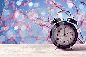 Spring time change concept with alarm clock over nature tree blossom